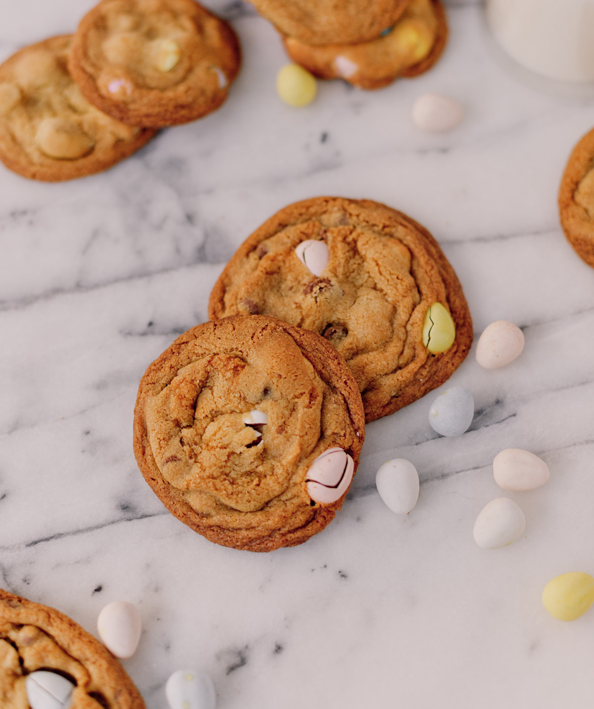 pile of cadbury chocolate chip cookies for easter with pastel colored easter candy inside, sitting on marble counter