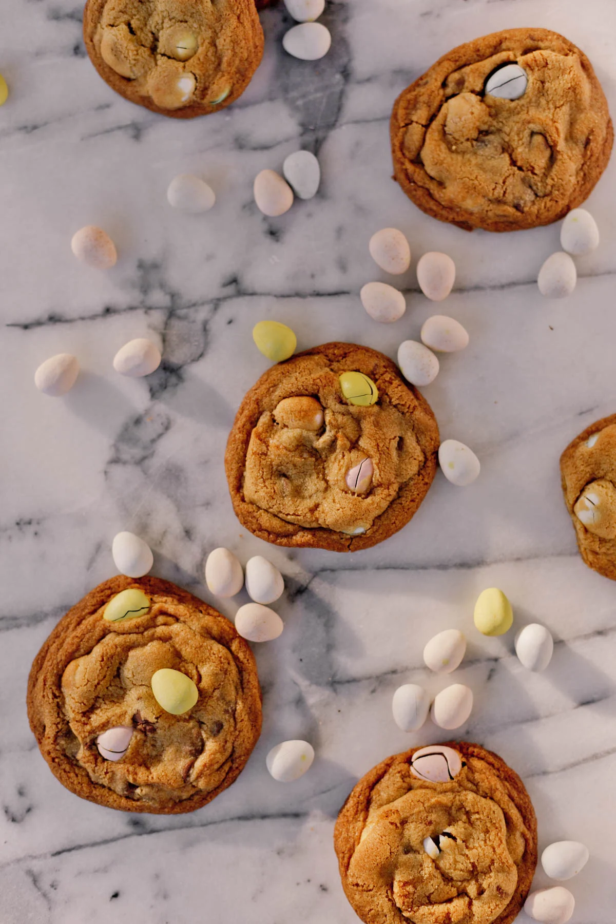cadbury chocolate chip cookies laid out on a marble counter with candy around it