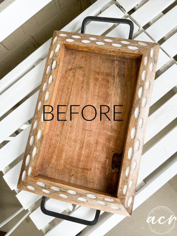 a rectangular wooden tray with metal handles and white oval accents sits on a white slatted surface. the word before is written across the center, awaiting its transformation with a makeover with napkin art.