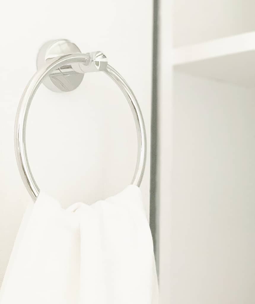 a minimalistic photo of a silver towel ring mounted on a white wall in a hallway makeover, holding a white towel, with soft lighting enhancing the simplicity and cleanliness of the scene.