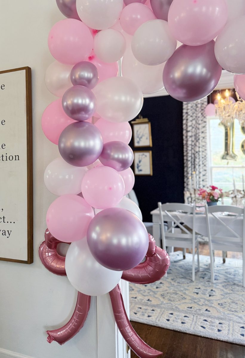 11 things i wish i bought sooner (april edition) 11 a garland of pink, white, and metallic purple balloons decorates a doorway, with a dining area in the background featuring white chairs, a chandelier, and floral accents.