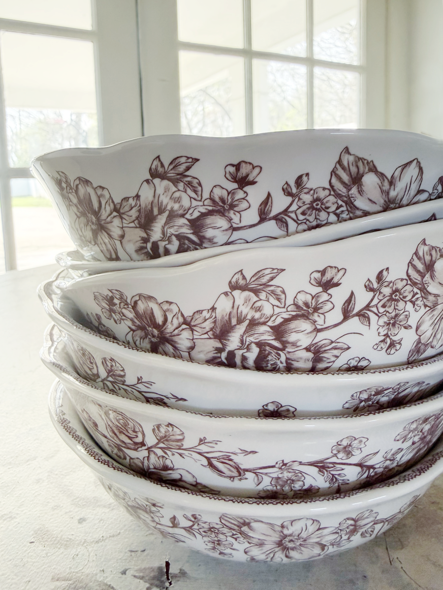 7 simple steps to style a hutch 29 a stack of white ceramic bowls with intricate dark floral patterns sits on a light surface near large windows, perfect to style a hutch with elegance and natural light.