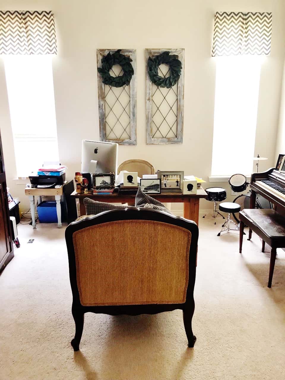a home office setup with a vintage desk painted in sea serpent by sherwin williams, facing two large windows flanked by decorative mirrors. the desk holds a computer and various items, and a classic