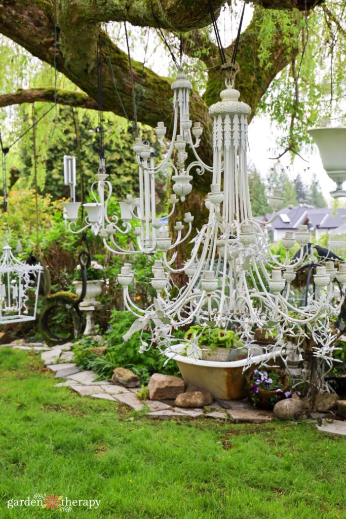 white chandeliers hanging from a mossy tree in the garden