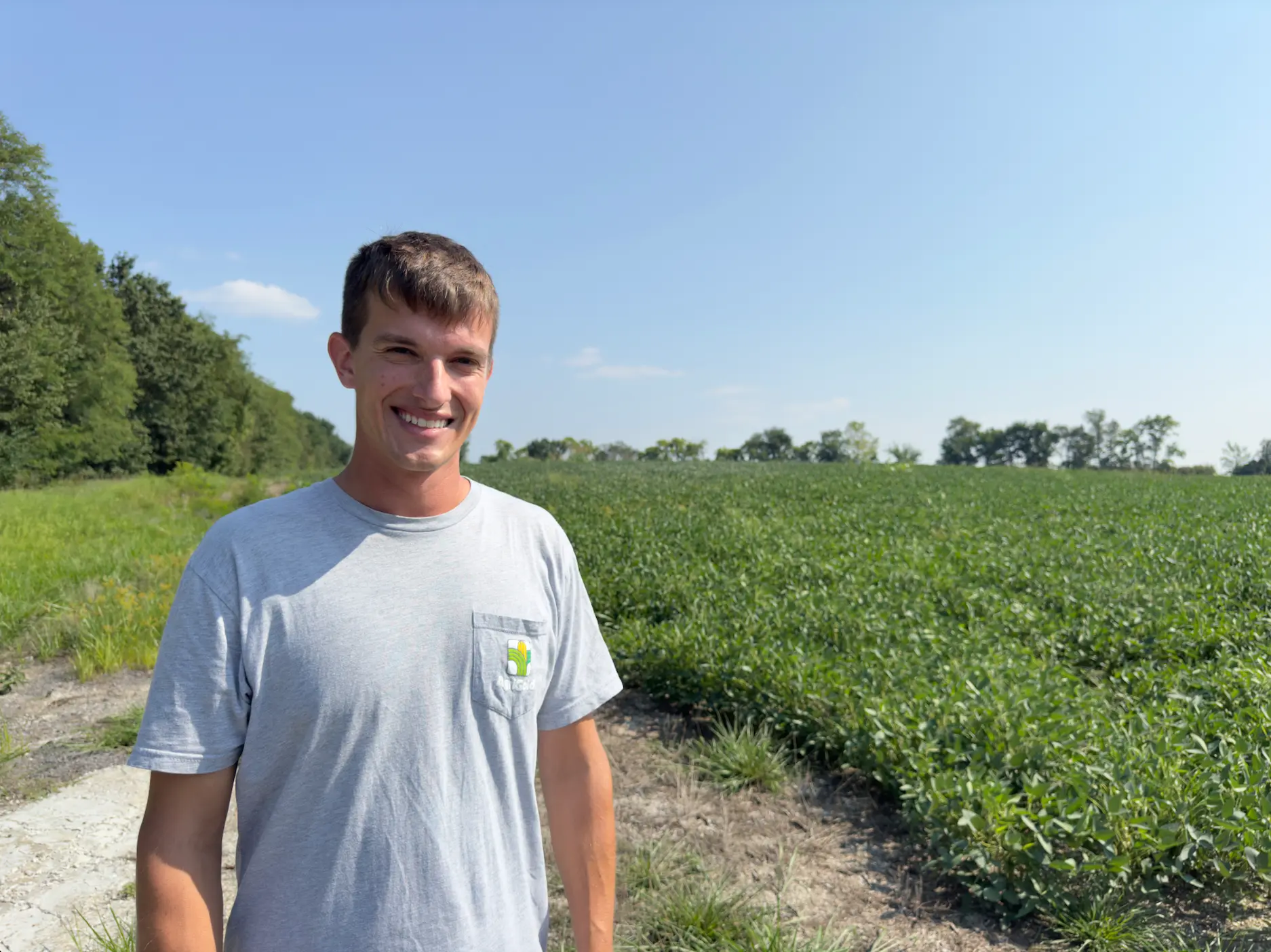 a young man stands in a field of green crops