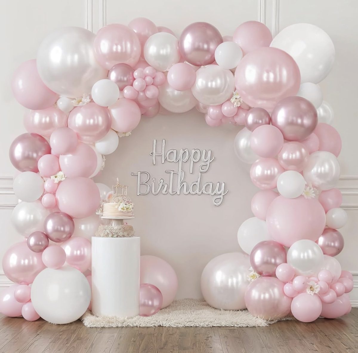 11 things i wish i bought sooner (april edition) 10 pink, white, and metallic balloons form an arch around a "happy birthday" sign. a white pedestal holds a cake and small treats, and the setup is placed on a soft beige rug in a light, elegant room.