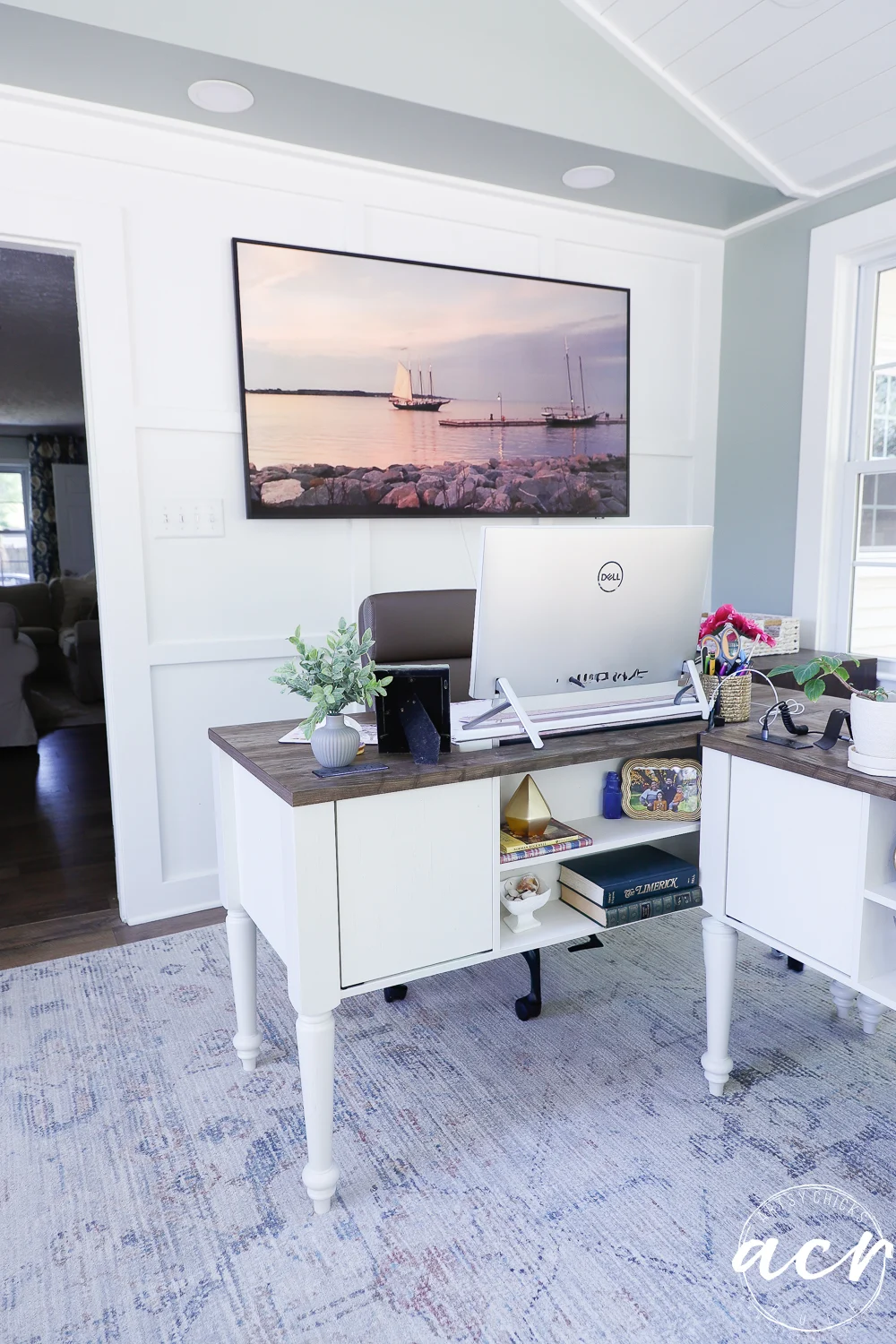 office reveal (sunroom) - artsy chicks rule® 65 a bright, modern home office reveal featuring a large monitor on a desk, white paneled walls, and a wall-mounted photo of sailboats. natural light streams in through the window, giving this sunroom-inspired space an airy and organized feel.