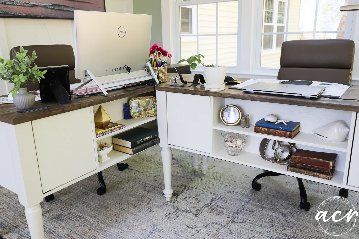 office reveal (sunroom) - artsy chicks rule® 67 two white desks arranged in an l-shape in a bright sunroom office, each with a chair, computer, plants, books, and decorative items. windows flood the space with natural light, while a patterned rug completes this stylish office reveal.