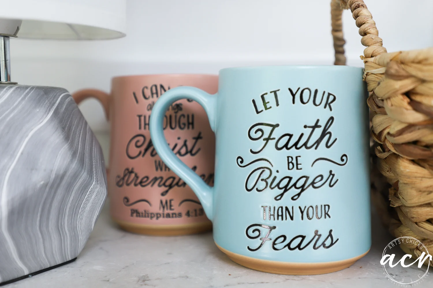 office reveal (sunroom) - artsy chicks rule® 71 two ceramic mugs sit on a countertop in a cozy sunroom. the front mug is light blue with the words let your faith be bigger than your fears, while the pink mug features an inspirational bible verse. a lamp and woven basket are nearby.