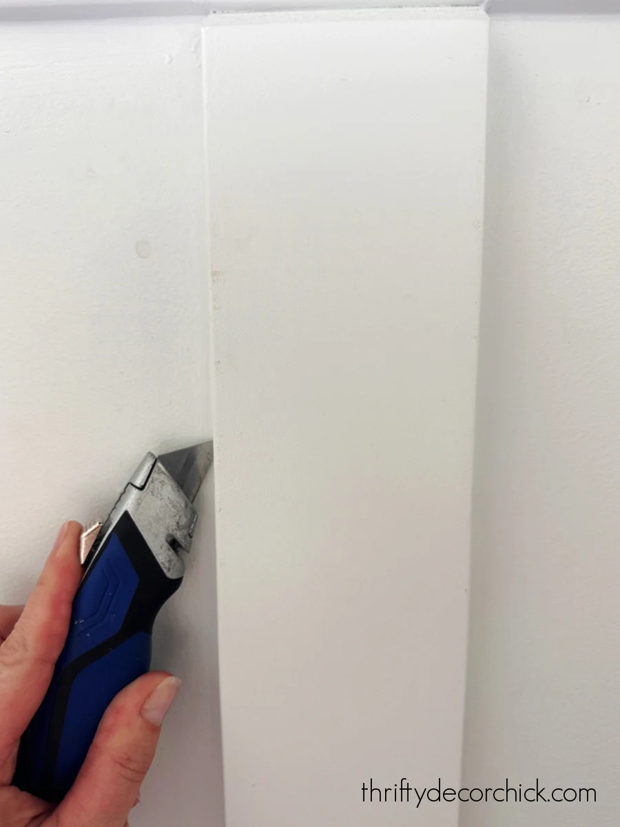 a pretty window diy and finishing touches in the powder room | thrifty decor chick 3 scoring caulk with razor blade