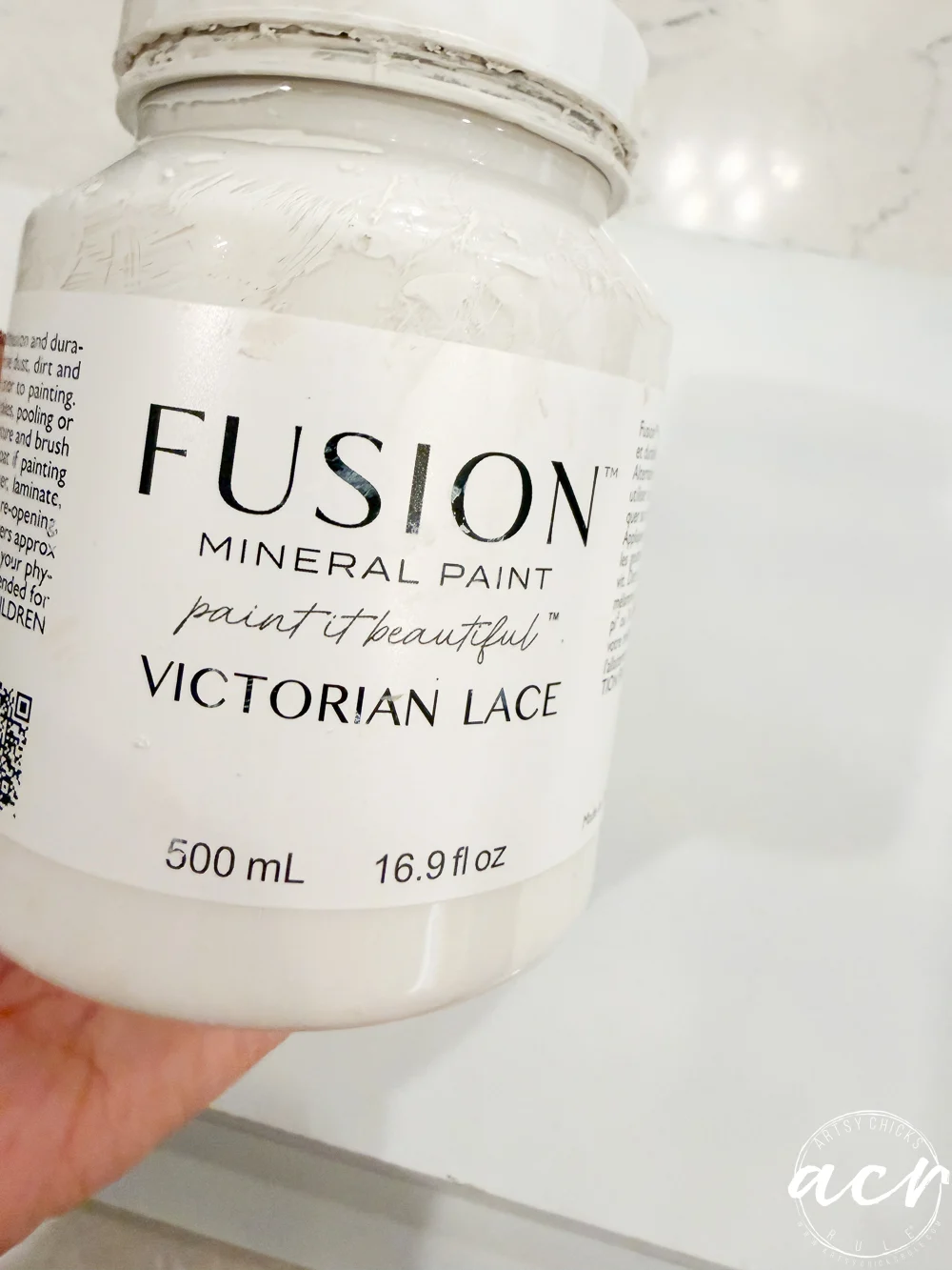 a hand holds a jar of fusion mineral paint in victorian lace, perfect for upcycling thrifted trays or adding charm to your home decor. the label reads 