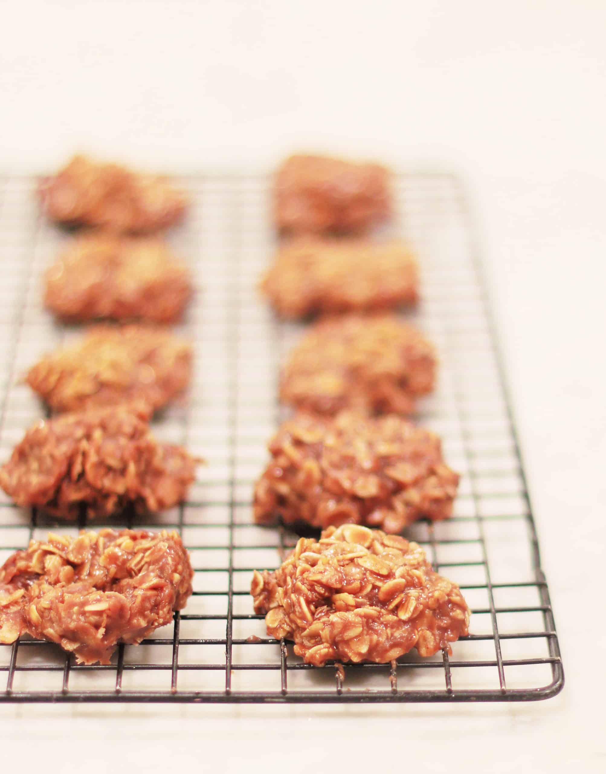 freshly baked oatmeal cookies cooling on a wire rack with a blurred white background.