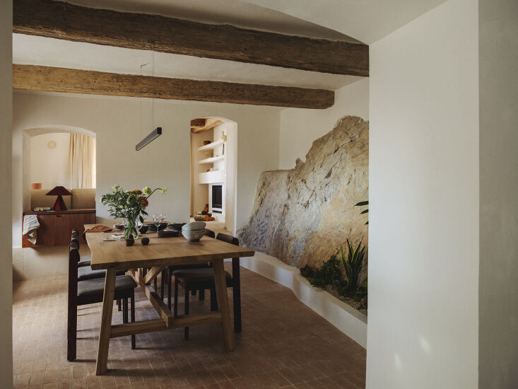 a farmhouse dining table sits parallel from the exposed stone of the hillside. 21