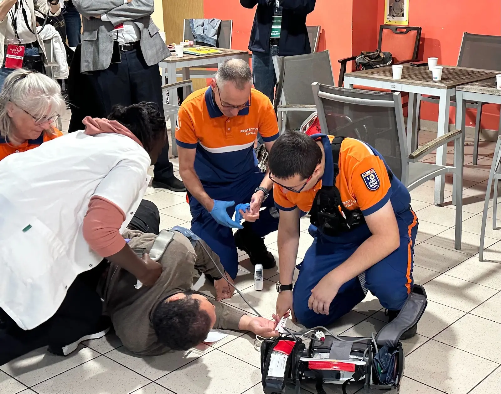 medics in orange shirts attend to a collapsed person