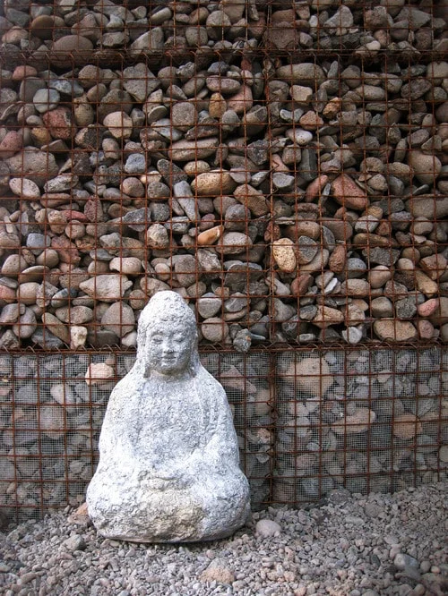 gabion garden wall with a buddha statue and layered stone texture