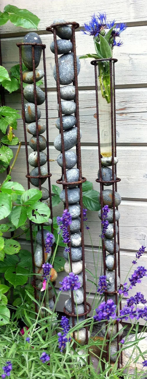 modern garden sculpture made with rebar and stacked stones surrounded by plants