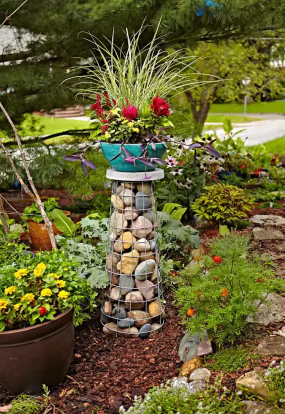 wire gabion filled with rocks used as a garden sculpture feature with plant stacked on it